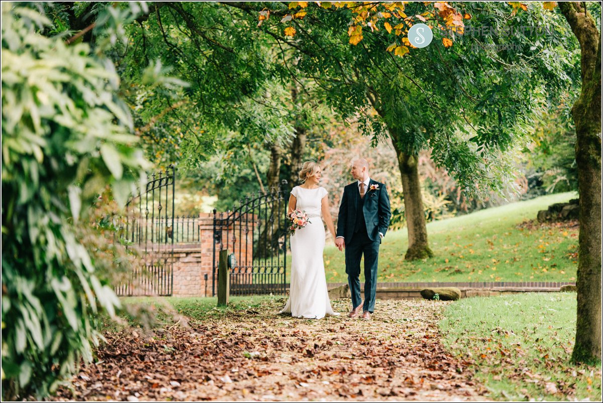 bride and groom walking through he beautiful autumn colours at Moddershall Oaks